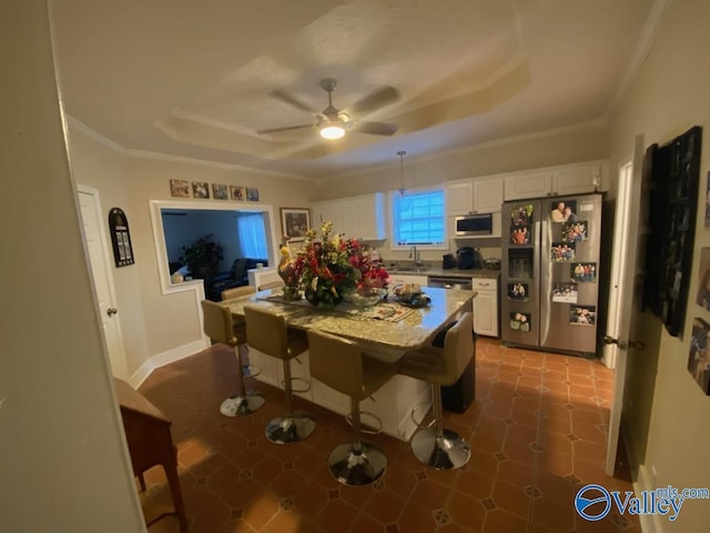 dining area featuring a tray ceiling, crown molding, baseboards, and ceiling fan