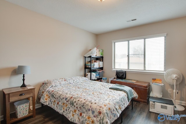 bedroom with a textured ceiling and dark wood-type flooring