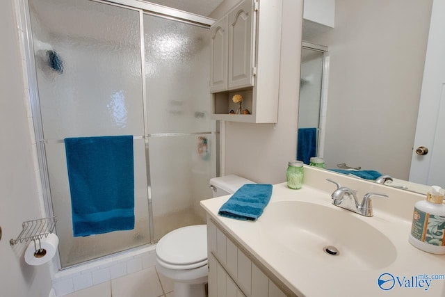 bathroom featuring tile patterned floors, vanity, a shower with shower door, and toilet