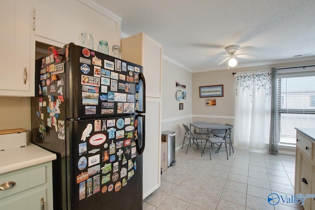 kitchen with ceiling fan, black refrigerator, light tile patterned flooring, and ornamental molding