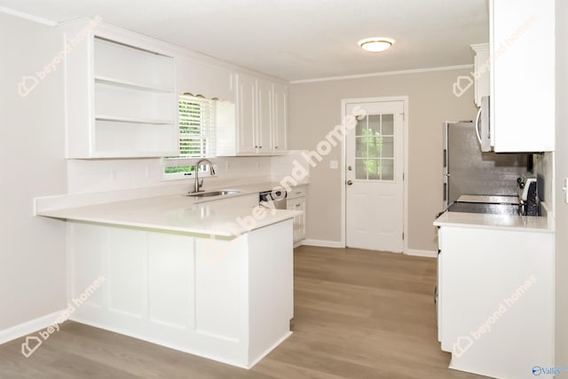 kitchen with sink, white cabinets, kitchen peninsula, stainless steel appliances, and backsplash