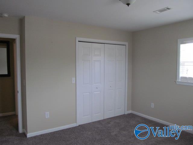 unfurnished bedroom with dark carpet and a closet