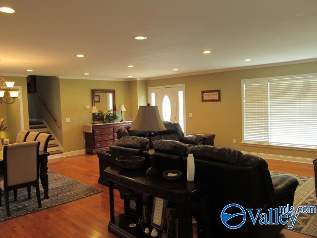 living room featuring crown molding, hardwood / wood-style floors, and an inviting chandelier