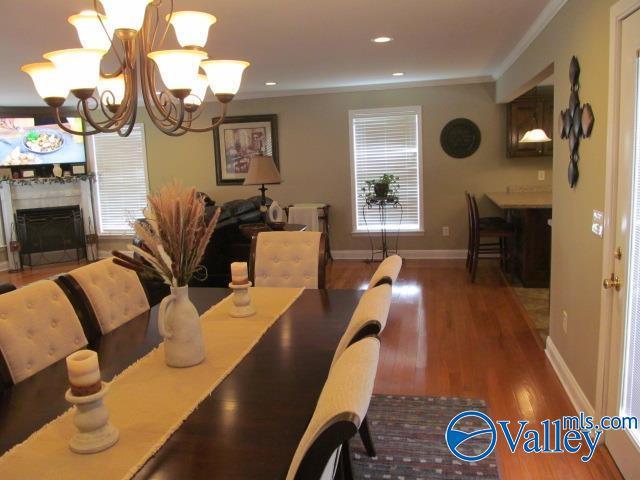 dining area with ornamental molding, a notable chandelier, and hardwood / wood-style floors