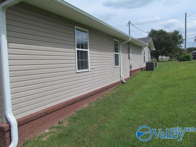 view of property exterior with central AC unit and a lawn