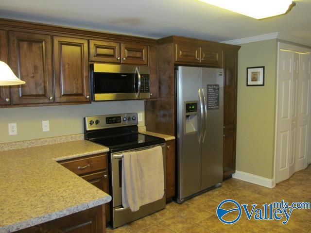 kitchen featuring dark brown cabinets, ornamental molding, and appliances with stainless steel finishes