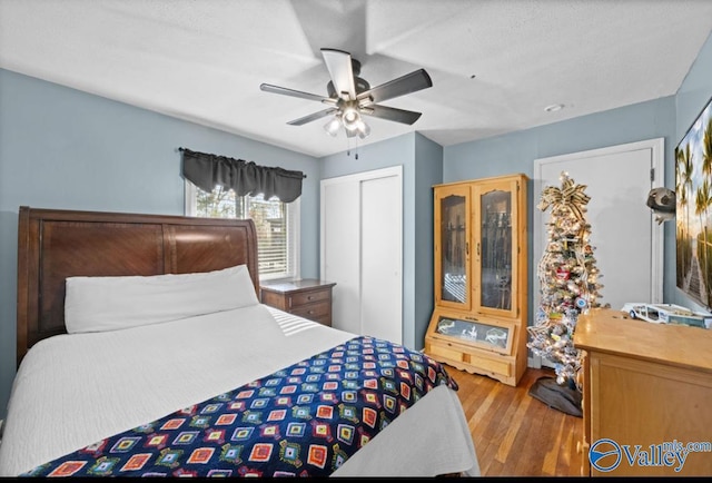 bedroom featuring a closet, ceiling fan, light hardwood / wood-style flooring, and a textured ceiling