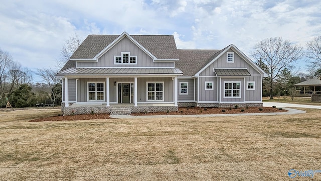 view of front facade with board and batten siding, a shingled roof, and a front yard