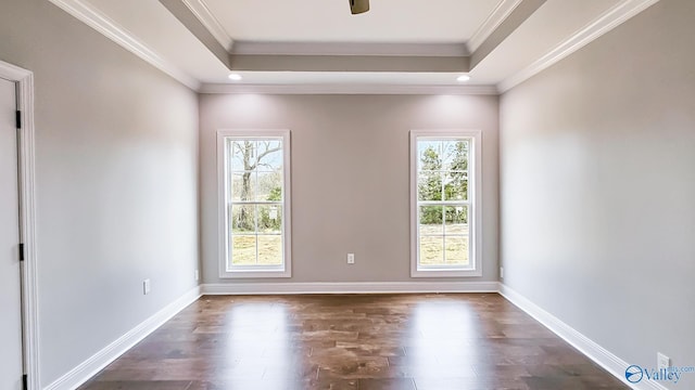 unfurnished room with a raised ceiling, dark wood-style flooring, and crown molding