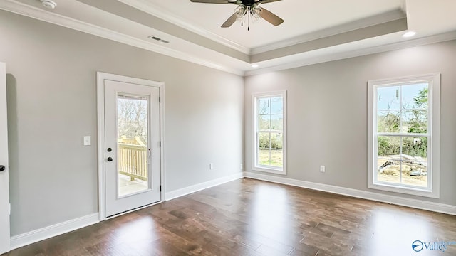 unfurnished room featuring a tray ceiling, visible vents, dark wood finished floors, and crown molding