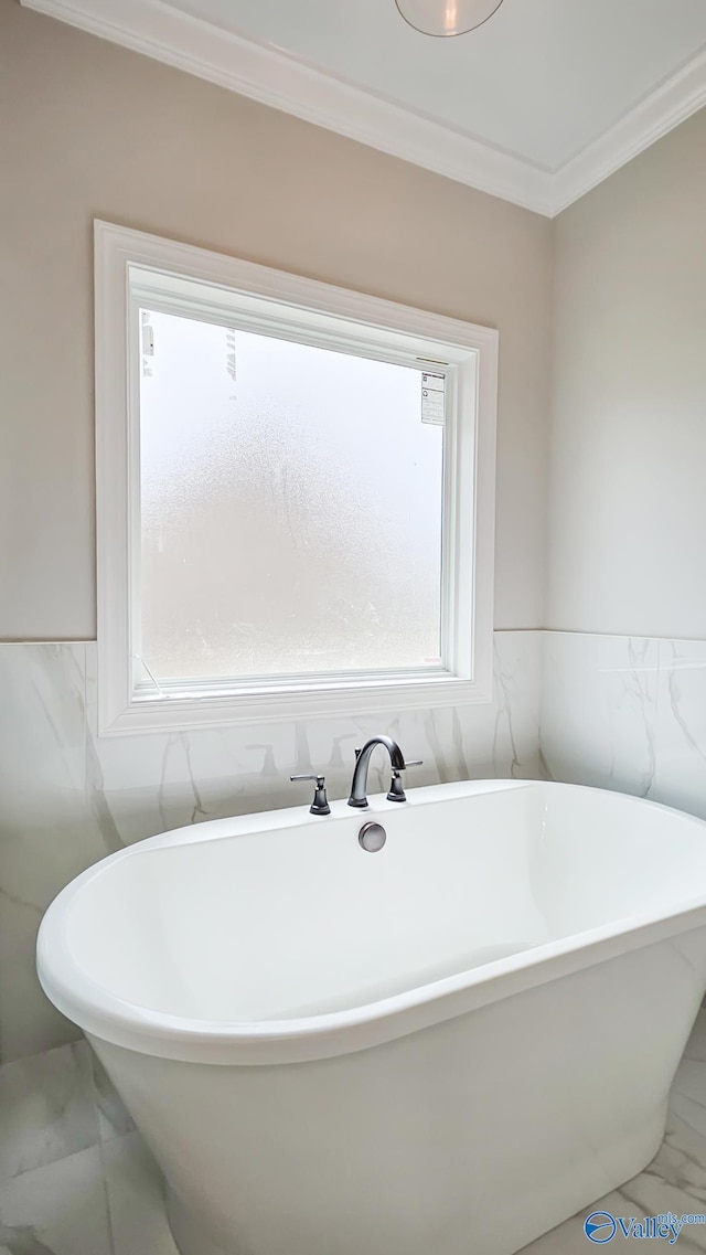 full bathroom with a wealth of natural light, a freestanding tub, marble finish floor, and ornamental molding