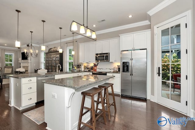 kitchen featuring dark wood-type flooring, white cabinetry, stainless steel appliances, a center island, and an inviting chandelier