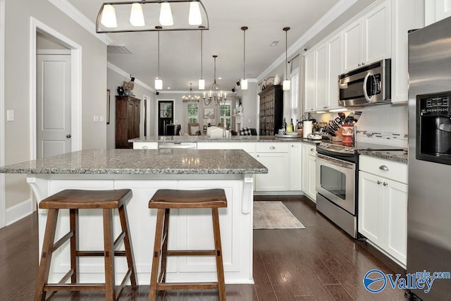 kitchen with a kitchen breakfast bar, hanging light fixtures, stainless steel appliances, dark stone counters, and dark hardwood / wood-style floors