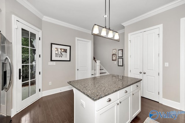 kitchen with white cabinets, hanging light fixtures, a kitchen island, dark wood-type flooring, and dark stone counters