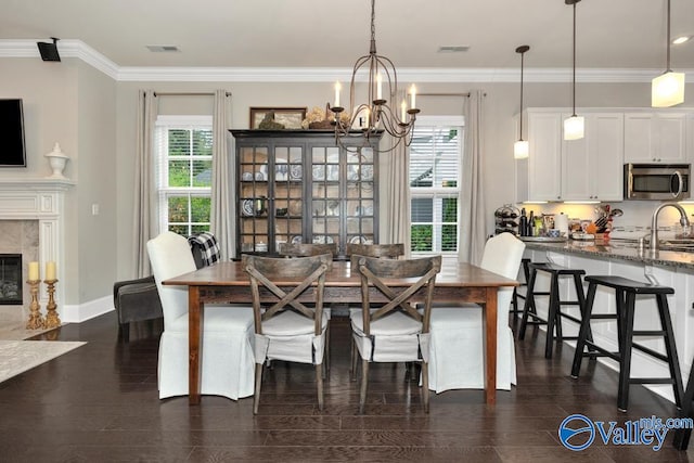 dining space with ornamental molding, a notable chandelier, dark hardwood / wood-style floors, and a premium fireplace