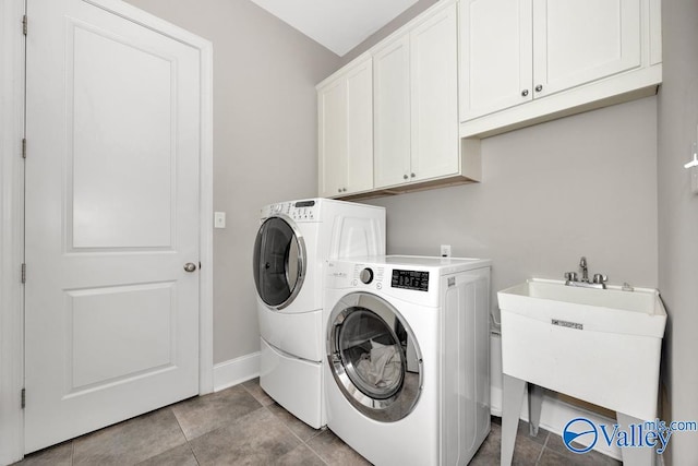 laundry room featuring washing machine and dryer, sink, light tile patterned floors, and cabinets