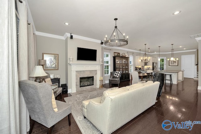 living room with an inviting chandelier, a tile fireplace, dark hardwood / wood-style floors, and crown molding