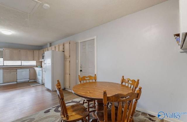 dining area featuring light wood finished floors, attic access, and baseboards