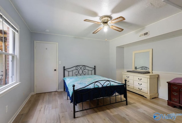 bedroom with light wood-style floors, visible vents, and multiple windows