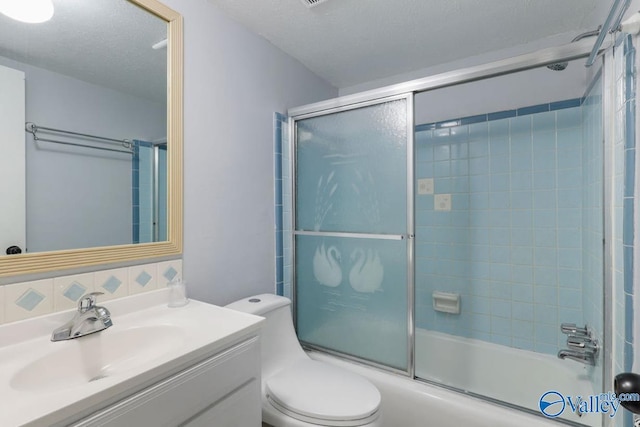 bathroom with combined bath / shower with glass door, vanity, toilet, and a textured ceiling