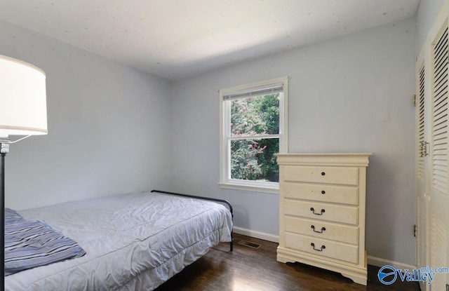 bedroom with visible vents, baseboards, and dark wood-type flooring