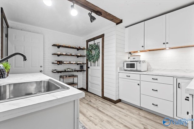 1081 County Road 190, Moulton, AL 35650 - kitchen with a sink, white microwave, backsplash, light wood finished floors, and white cabinets