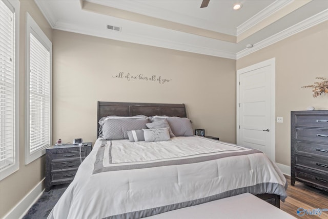 bedroom with a tray ceiling, ceiling fan, dark wood-type flooring, and ornamental molding