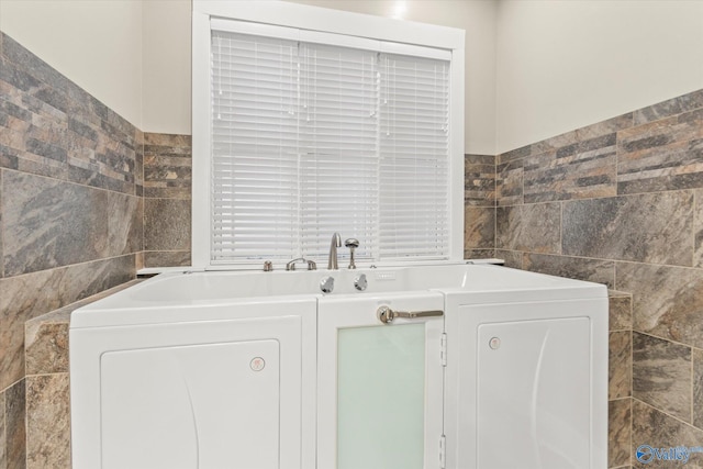 clothes washing area with tile walls