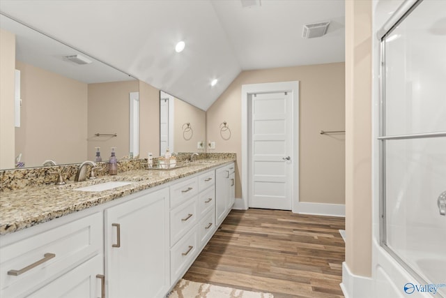 bathroom with hardwood / wood-style floors, vanity, a shower with shower door, and vaulted ceiling