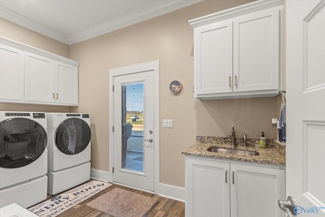 clothes washing area featuring cabinets, crown molding, sink, hardwood / wood-style floors, and washing machine and dryer