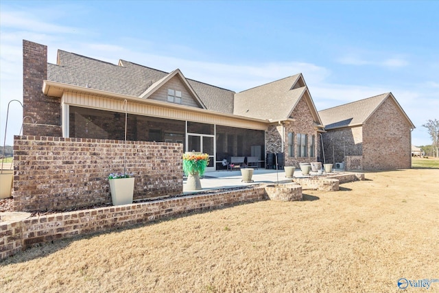 back of house featuring a lawn, a sunroom, and a patio