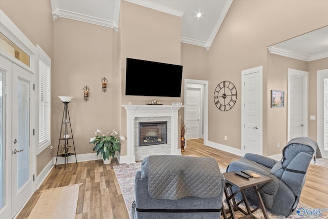 living room featuring a towering ceiling, crown molding, and light hardwood / wood-style flooring