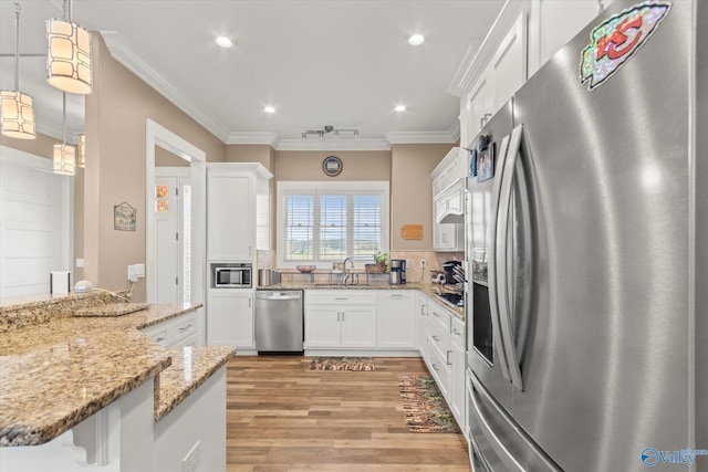 kitchen featuring white cabinetry, hanging light fixtures, stainless steel appliances, backsplash, and kitchen peninsula