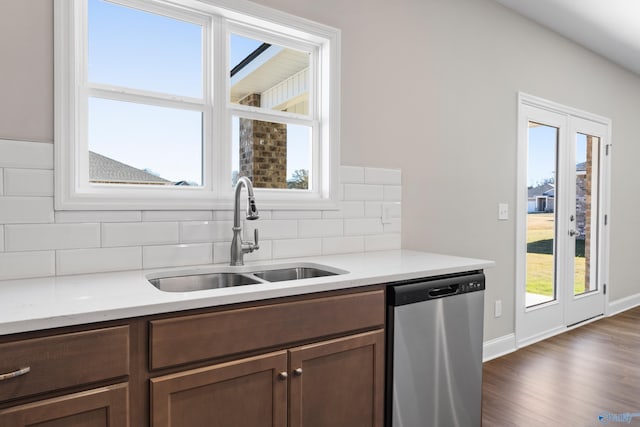 kitchen with baseboards, dishwasher, dark wood-style floors, backsplash, and a sink