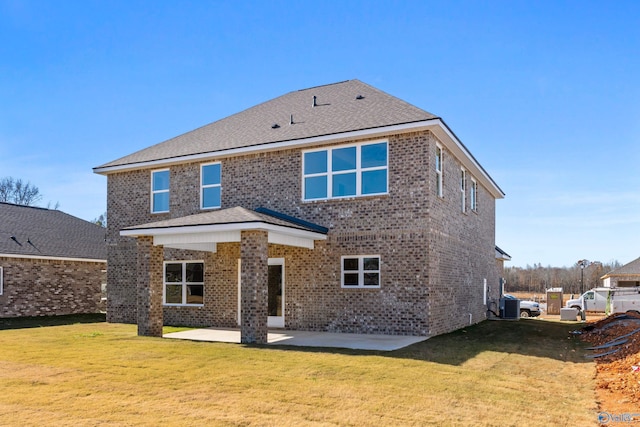 rear view of property with brick siding, a patio, a shingled roof, a lawn, and central AC unit