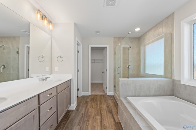 full bathroom with a garden tub, a sink, visible vents, a shower stall, and a walk in closet