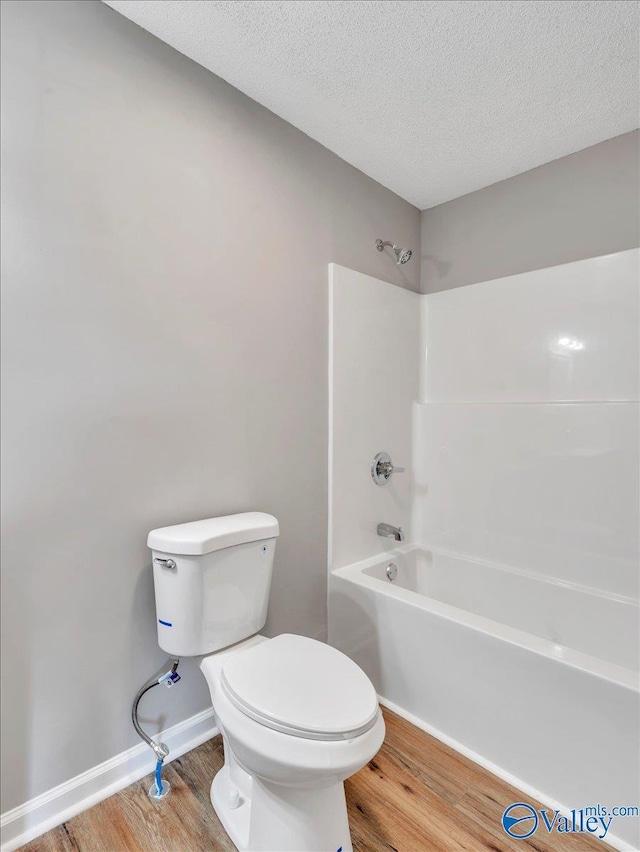 1492 County Road 314, Town Creek, AL 35672 - bathroom with wood finished floors, toilet, tub / shower combination, a textured ceiling, and baseboards