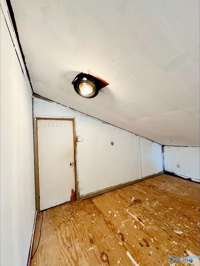 bonus room featuring a textured ceiling, lofted ceiling, and light hardwood / wood-style flooring