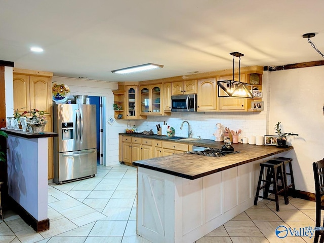 kitchen featuring hanging light fixtures, tasteful backsplash, kitchen peninsula, stainless steel appliances, and sink