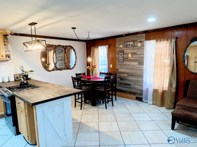 tiled dining space with ornamental molding and wood walls