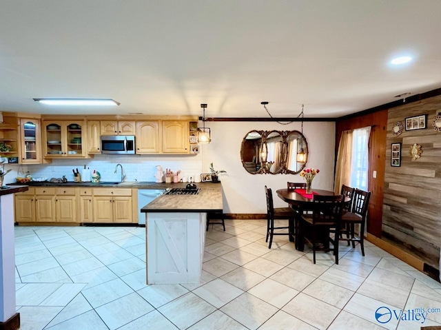 kitchen with hanging light fixtures, tasteful backsplash, white dishwasher, ornamental molding, and wooden walls