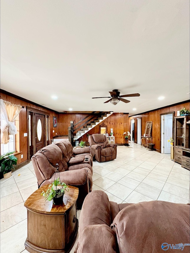 living room featuring wooden walls, ceiling fan, and light tile patterned flooring