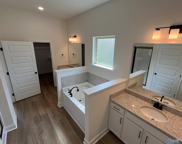 bathroom with hardwood / wood-style flooring, vanity, and a tub