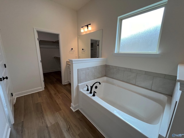 bathroom with wood-type flooring, a washtub, and vanity