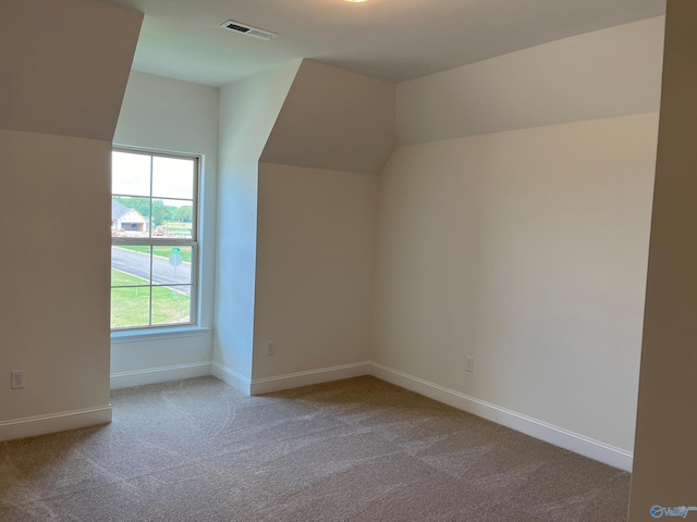 bonus room with lofted ceiling and light colored carpet