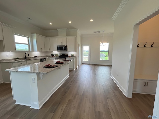 kitchen with light stone countertops, a center island, white cabinets, and appliances with stainless steel finishes