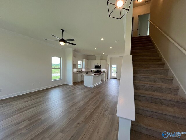 stairway featuring sink, wood-type flooring, a healthy amount of sunlight, and ceiling fan