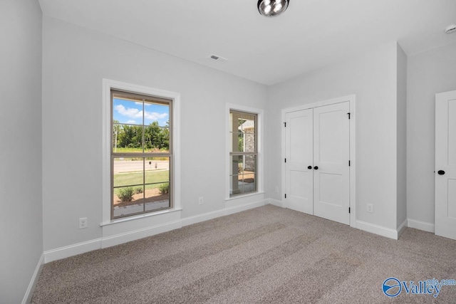 unfurnished bedroom featuring multiple windows, carpet floors, and a closet