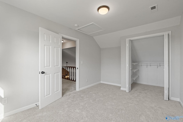 unfurnished bedroom featuring light colored carpet, lofted ceiling, and a closet