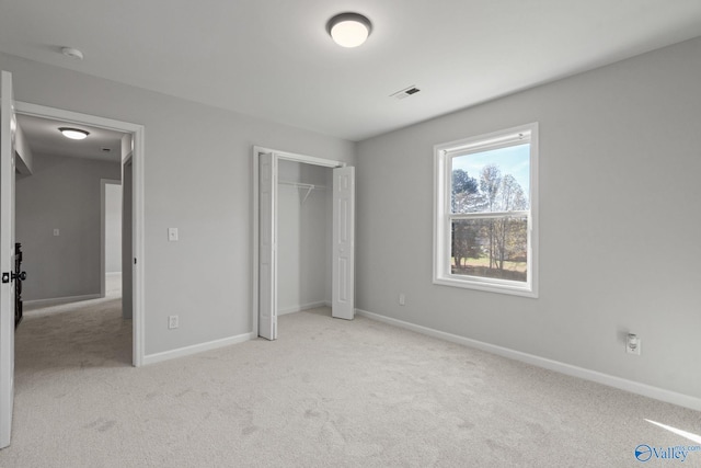 unfurnished bedroom with light carpet and a closet